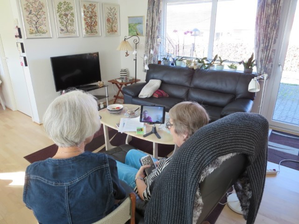 to kvinder sidder med en ipad og har en samtale 
