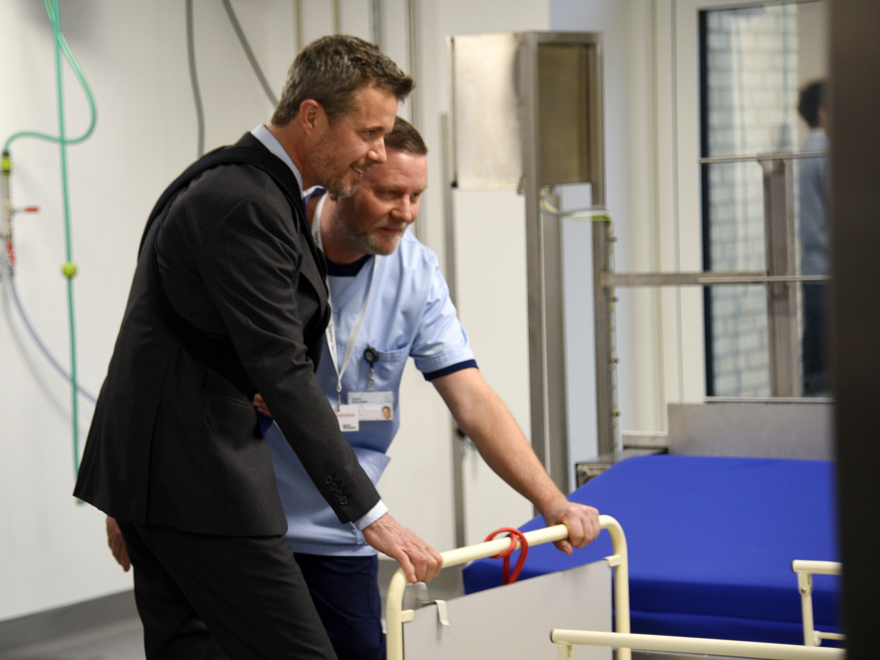 Kronprinsen hjælper portør Finn Pedersen med at skubbe en seng ind i sengevaskeren.