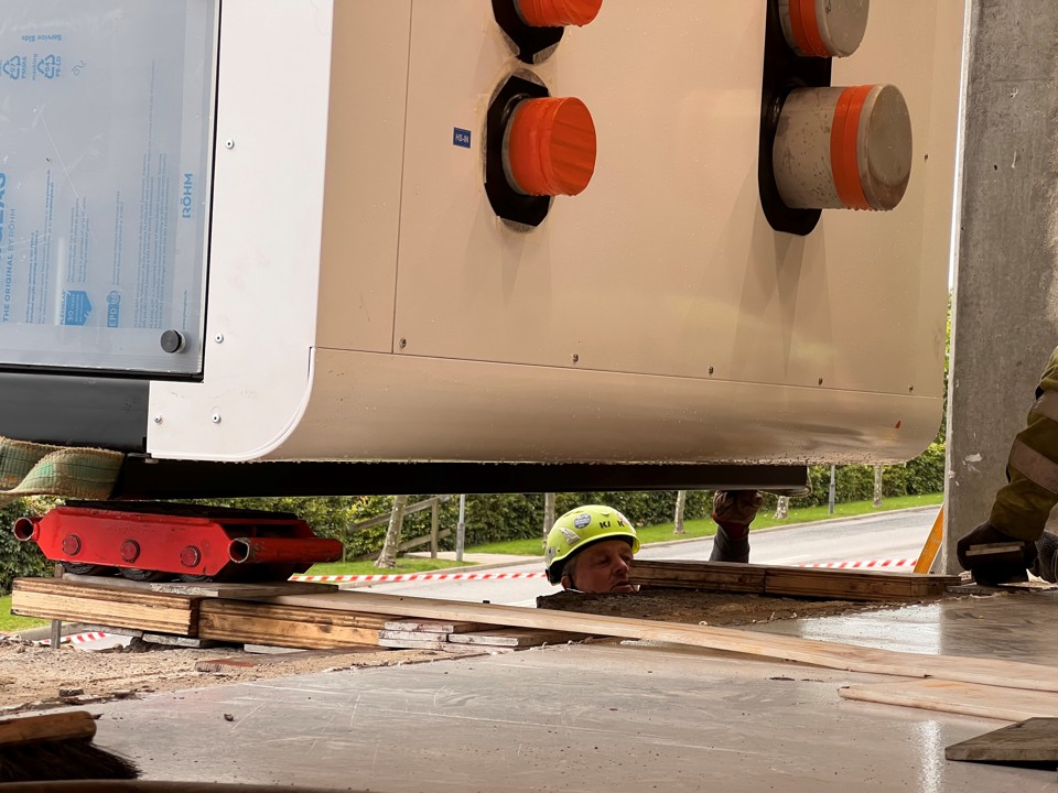 Kranfolk ses umiddelbart ved siden af varmepumpe i luften