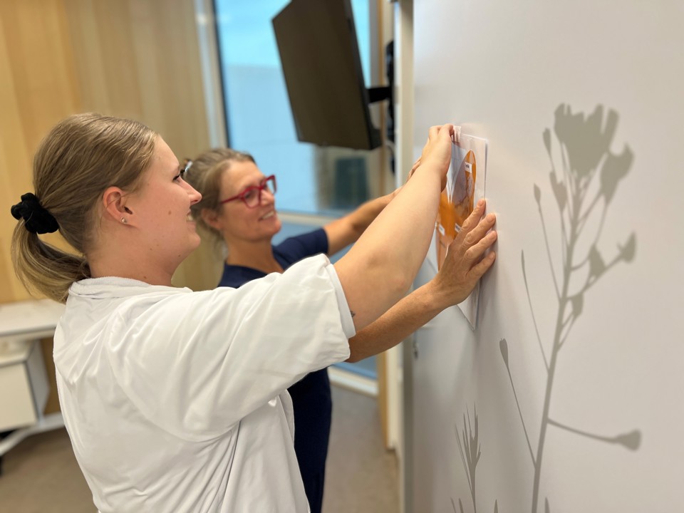 Ditte og Jasmin står ved væg med sommerfuglen